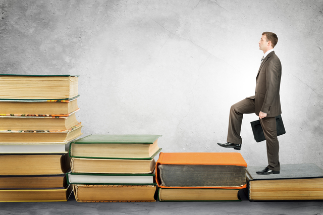Businessman with portfolio goes up stairs of books