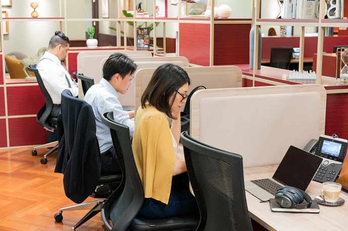 フリーアドレスのオフィスで仕事をする人たちの画像