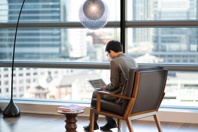 サーブコープ、ヤンマー東京の絶景が見えるコワーキングスペースを利用しながら働く男性ビジネスパーソン