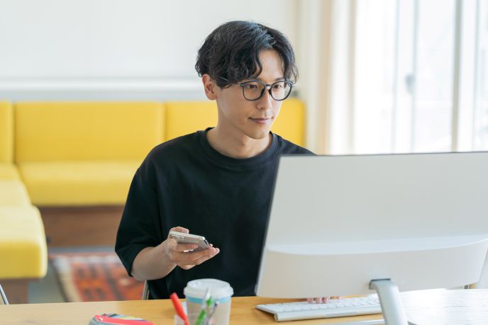 本社とは異なる場所に設けられるサテライトオフィスでリモートワークをしている男性のビジネスパーソンのイメージ