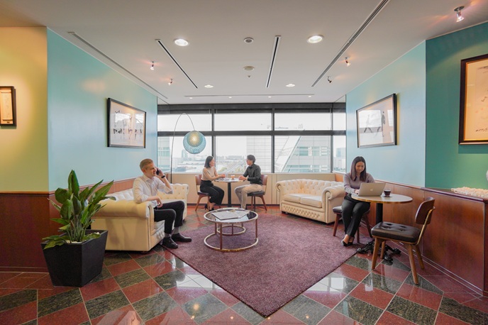 サーブコープ有明フロンティアビルにあるプレミアムラウンジで、仕事や電話を行うビジネスパーソン