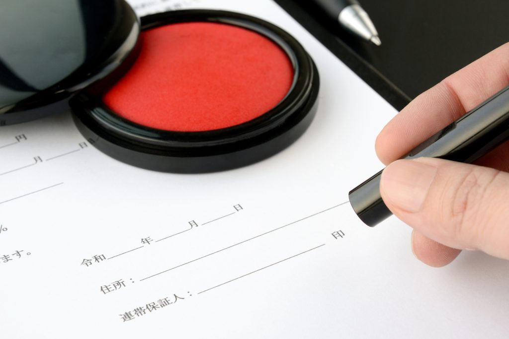 会社設立や法人登記の書類に押印する様子を写したイメージ。大阪での登記手続きの流れを示す場面。