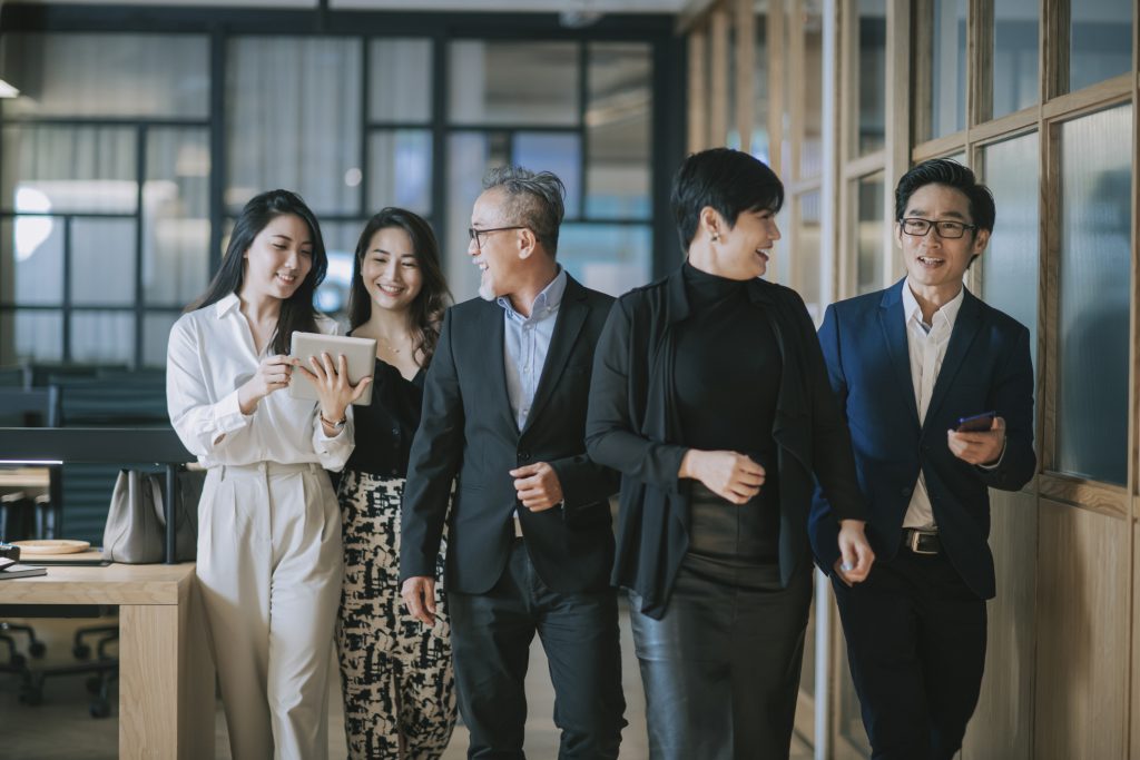 モダンなオフィス空間で歩きながらコミュニケーションを取るビジネスパーソンたち