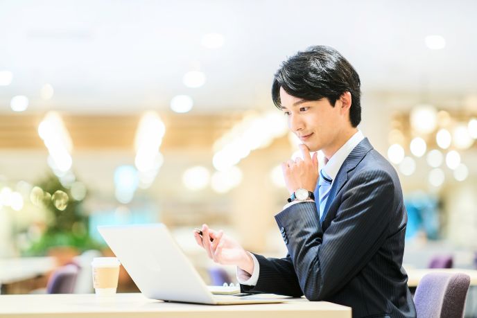 AI技術の導入を検討する男性ビジネスパーソンが、コワーキングスペースでノートパソコンを使用している様子