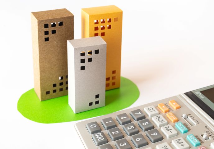 資本金の決め方と注意点をビルと電卓で表しているイラスト