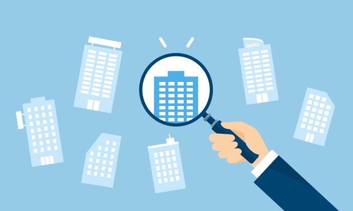 さまざまな企業を虫眼鏡で拡大する男性の手