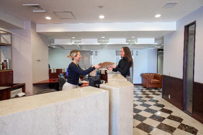 サーブコープのレセプショニストから会社設立に必要なアイテムを受け取るビジネスパーソン