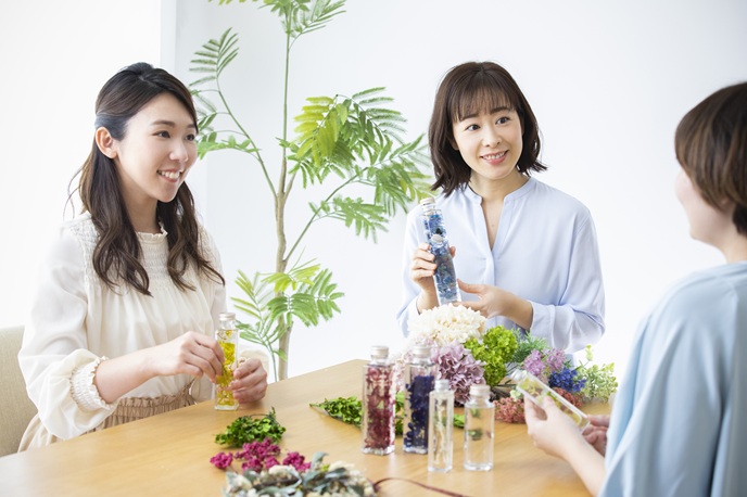 趣味のハーバリウムの作り方を友人に教えているビジネスパーソン